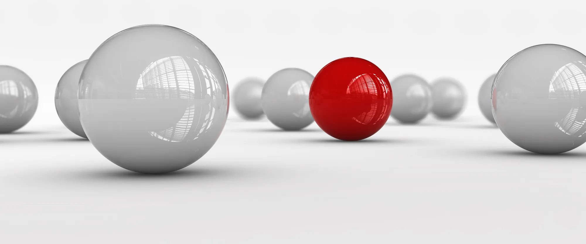 A red ball in a row of silver balls