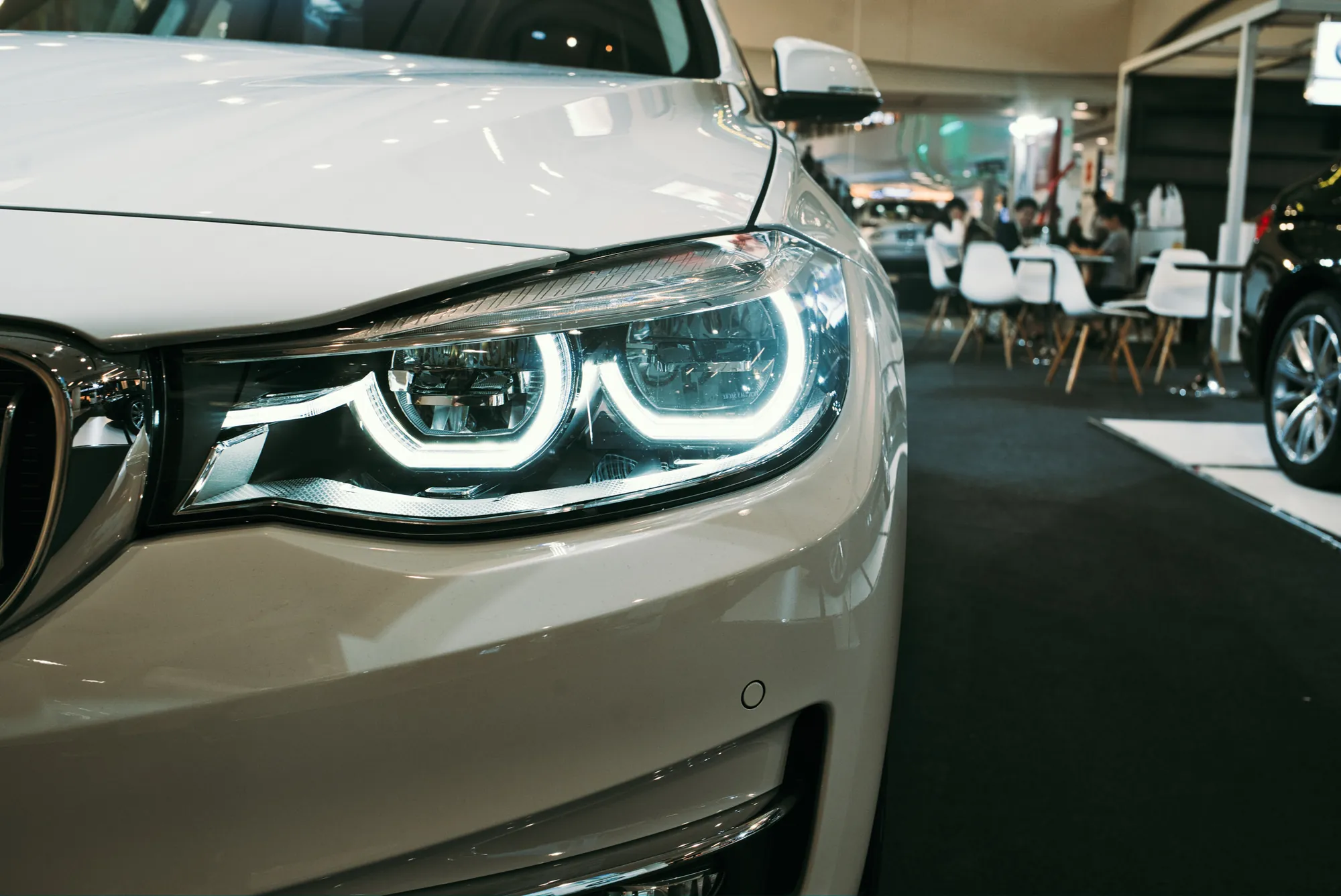 Scheinwerfer eines weißen Autos in einem Ausstellungsraum
